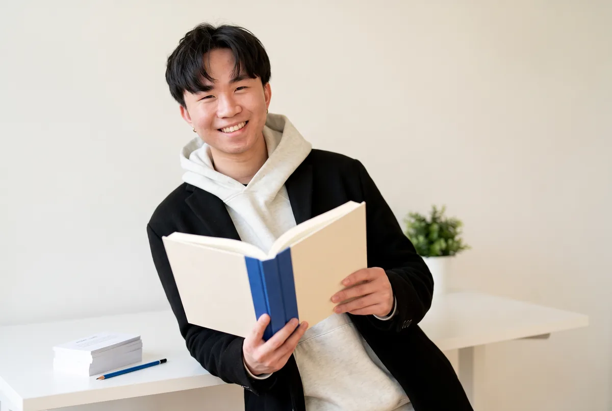 Ray Fu holding an open workbook beside a stack of prompt cards